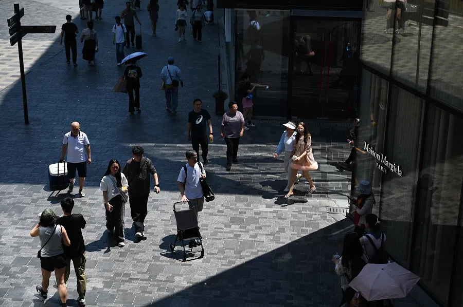 People walk past stores in a shopping mall in Beijing on 8 June 2025. (Greg Baker/AFP)