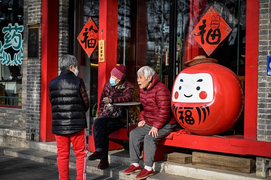 Elderly people chat outside a restaurant along a street in Beijing, China, on 16 March 2023. (Jade Gao/AFP)