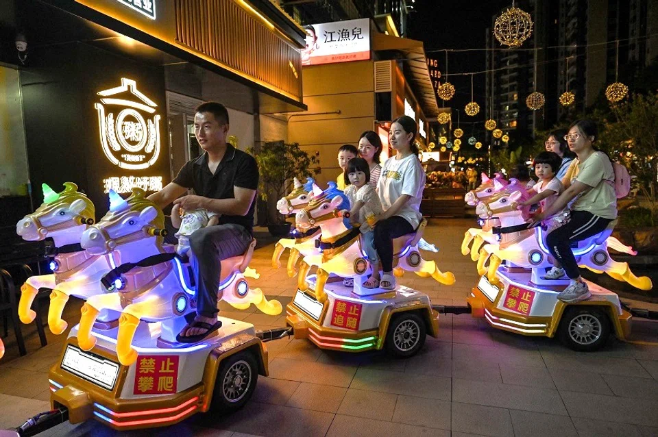 People ride a small train for children on a street in Guangzhou, Guangdong province, China on 16 September 2023. (Hector Retamal/AFP)