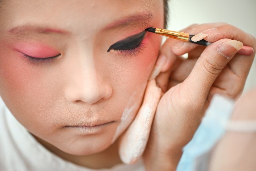 A young Chinese opera performer puts on makeup, 7 August 2022. Chinese Singaporeans are still searching for their identity. (SPH Media)