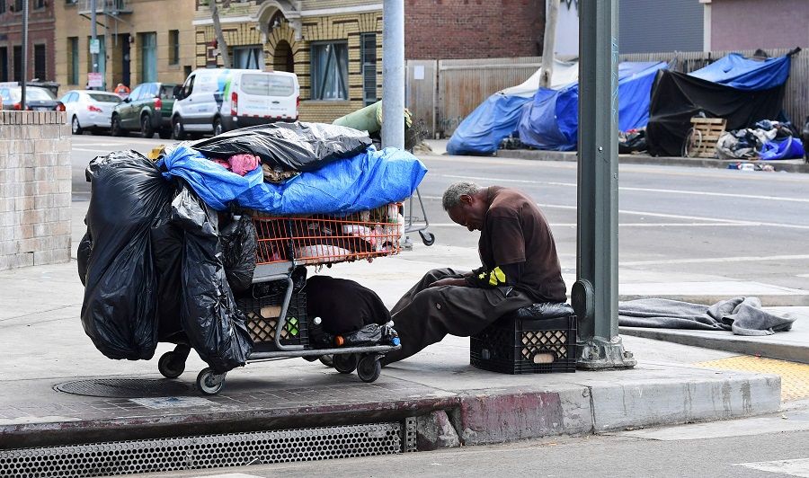 A homeless man sits beside his belongings on the streets in the Skid Row community of Los Angeles, California on 26 April 2021. (Frederic J. Brown/AFP)