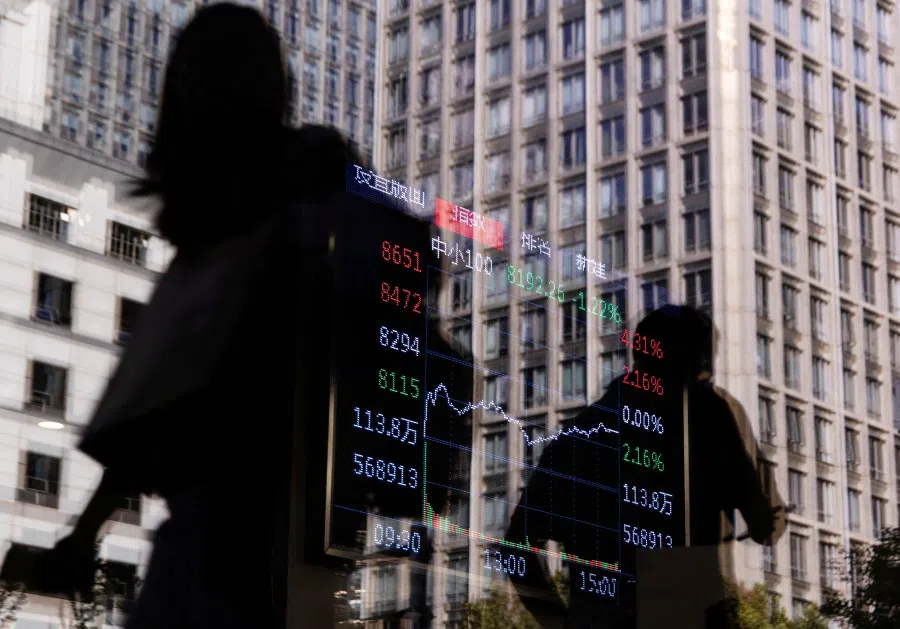 People walk past a brokerage house, as an electronic board displays stock index information graph, in the Central Business District (CBD) in Beijing, China, 13 October 2025. (Maxim Shemetov/Reuters)