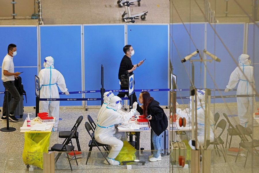 Medical workers in protective suits gather swabs from passengers for nucleic acid testing, at an arrival hall of Shanghai Hongqiao International Airport, following a Covid-19 outbreak in Shanghai, China, 12 October 2022. (CNS photo via Reuters)