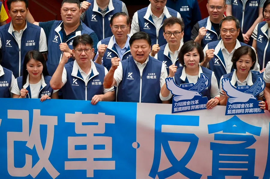 Lawmakers from the main opposition Kuomintang (KMT) display a banner reading “Parliament reform and anti-corruption” after voting for reconsidering controversial bills at Parliament in Taipei, Taiwan, on 21 June 2024. (Sam Yeh/AFP)