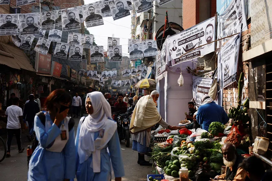Posters of an election candidate hang on the street as people buy vegetables from a street vendor ahead of the general election in Dhaka, Bangladesh, on 2 January 2024. (Mohammad Ponir Hossain/Reuters)