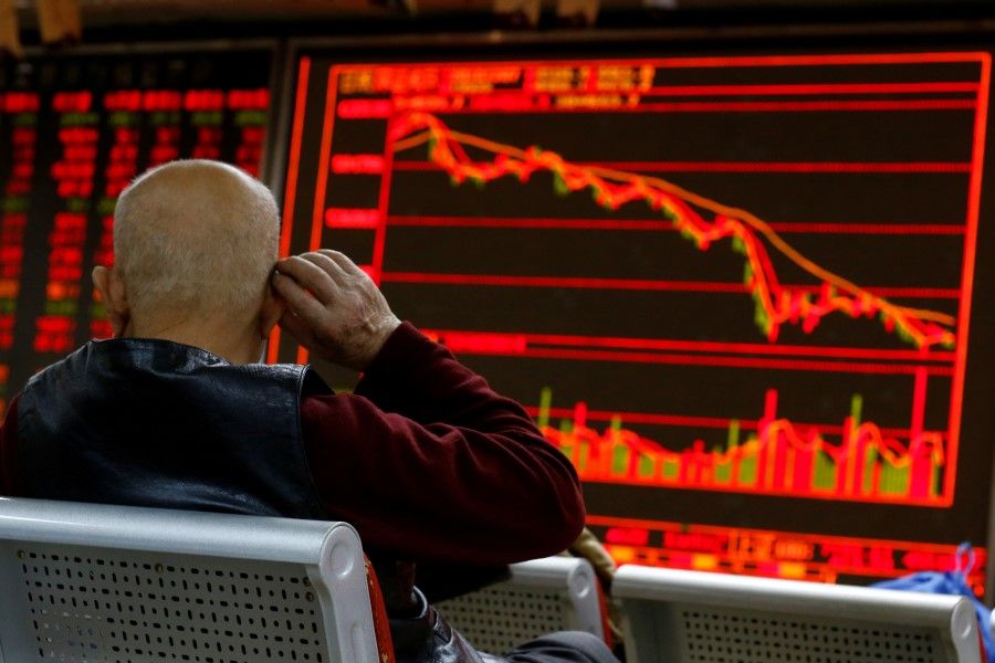 An investor sits in front of a board showing stock information at a brokerage office in Beijing, China, 7 December 2018. (Thomas Peter/Reuters)