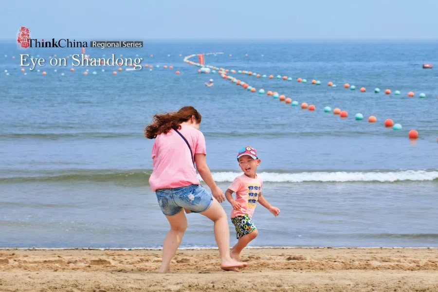 A woman has fun with her playful young boy on Yantai beach. Because of its fair weather, extensive coastline and abundant tourist sites, Yantai in Shandong province is a very popular summer retreat.