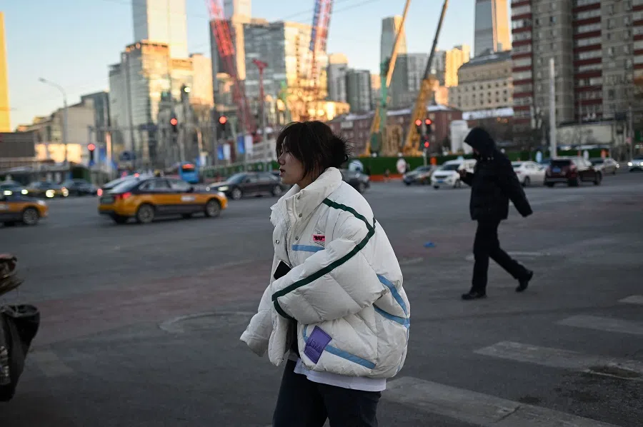 A woman crosses a street in Beijing, China, on 19 December 2023. (Wang Zhao/AFP)