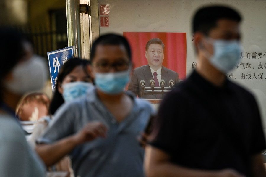 People line up to be tested for Covid-19 next to a poster showing China's President Xi Jinping on a bulletin board in Beijing, China, on 31 August 2022. (Jade Gao/AFP)