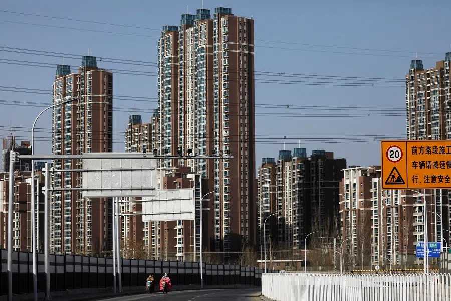 People ride scooters past residential buildings in Beijing, China, 13 January 2021. (Tingshu Wang/Reuters)