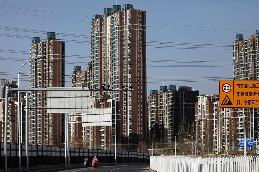 People ride scooters past residential buildings in Beijing, China, 13 January 2021. (Tingshu Wang/Reuters)