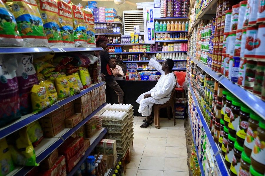 A grocery shop owner chats with friends in Khartoum, the capital of Sudan, on 19 January 2023. (Ashraf Shazly/AFP)