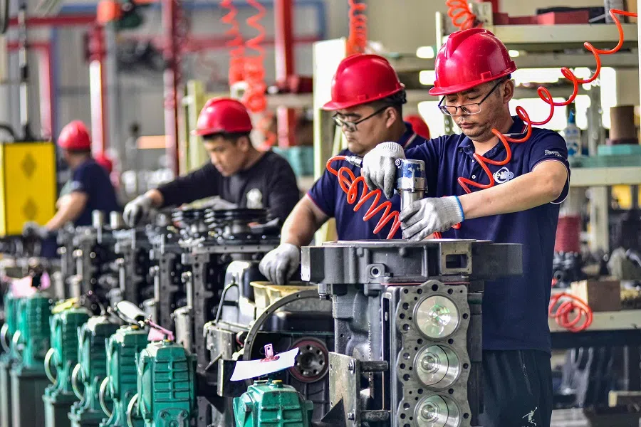 Employees work on an engine assembly line at an engine manufacturing factory in Qingzhou, in China’s eastern Shandong province, on 16 April 2024. 
