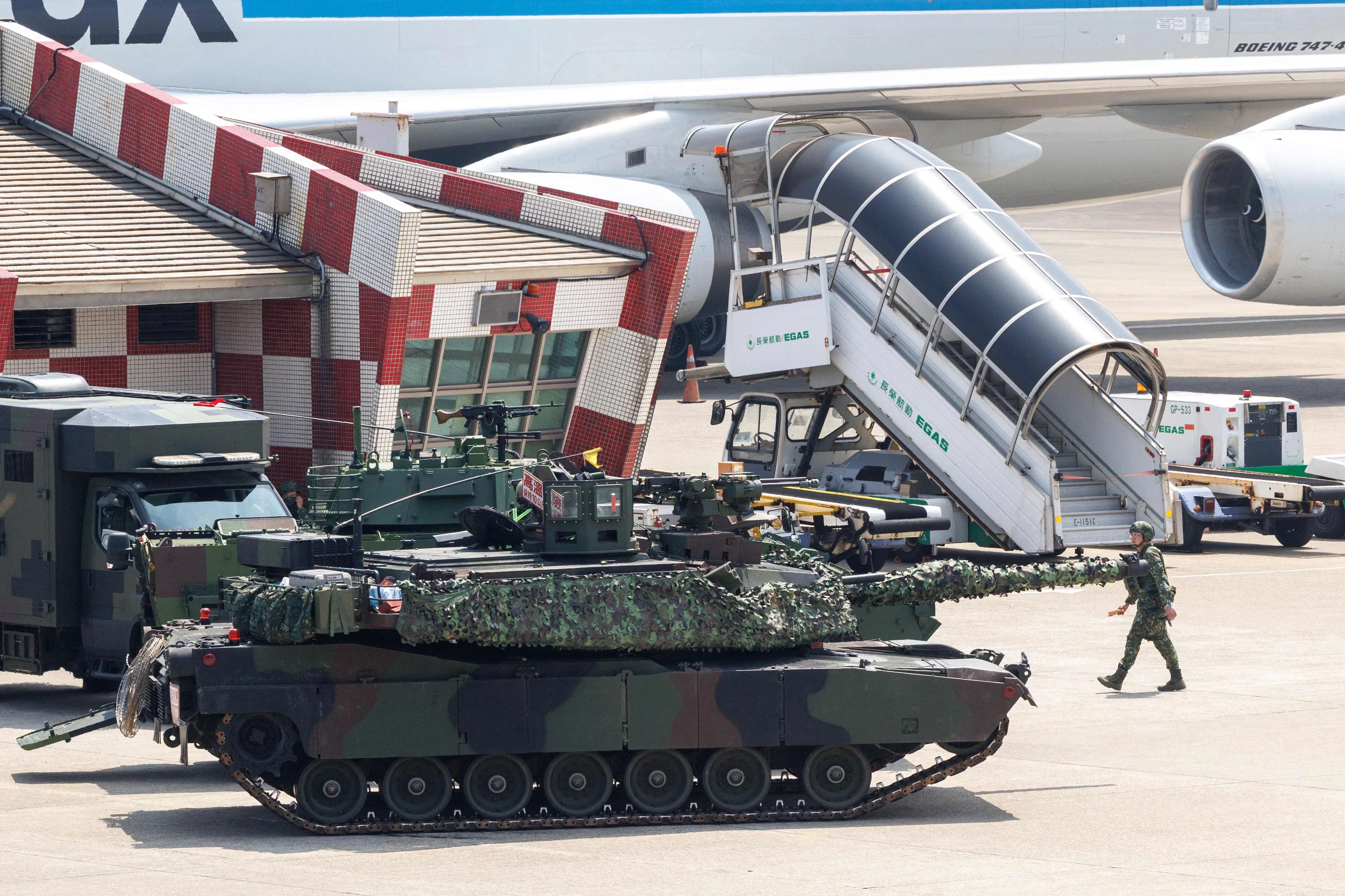 A Taiwanese military M1A2T tank is pictured next to aircraft during a drill simulating an enemy airborne assault at Taiwan Taoyuan International Airport in Taoyuan on 7 August 2026.