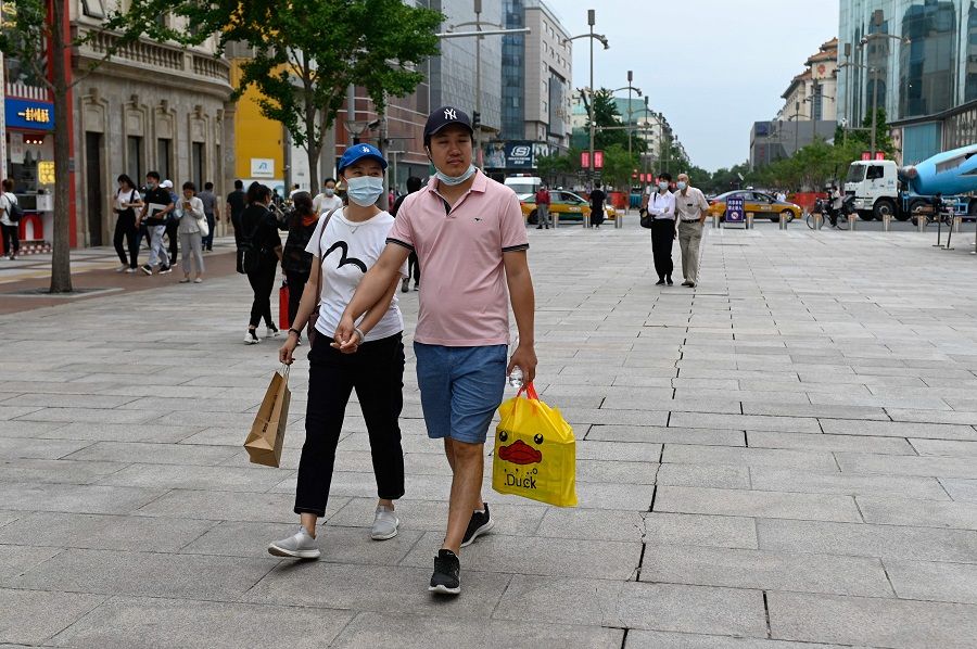 A couple visit a business street in Beijing, China, on 15 September 2021. (Wang Zhao/AFP)