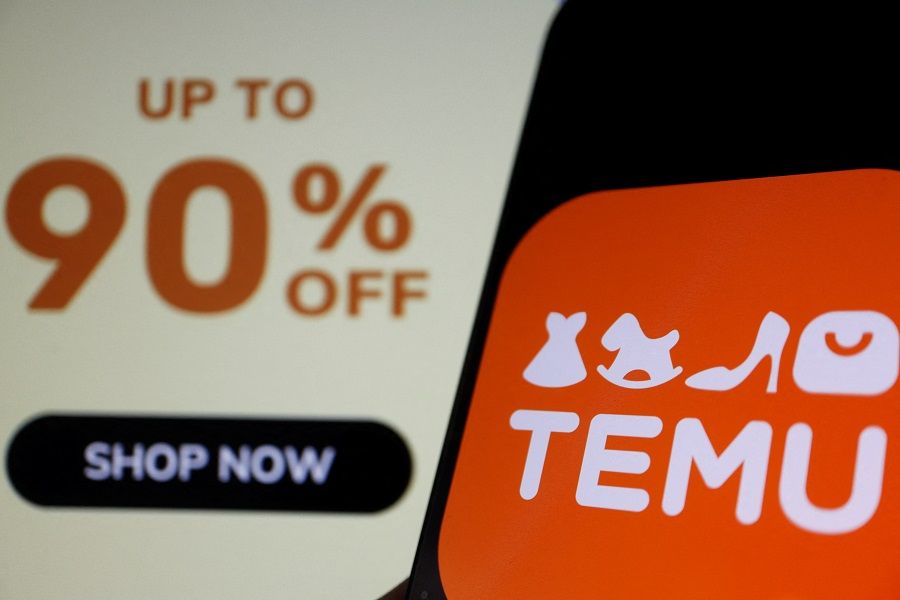 The logo of Temu, an e-commerce platform owned by PDD Holdings, is seen on a mobile phone displayed in front of its website, in this illustration picture taken 26 April 2023. (Florence Lo/Illustration/Reuters)
