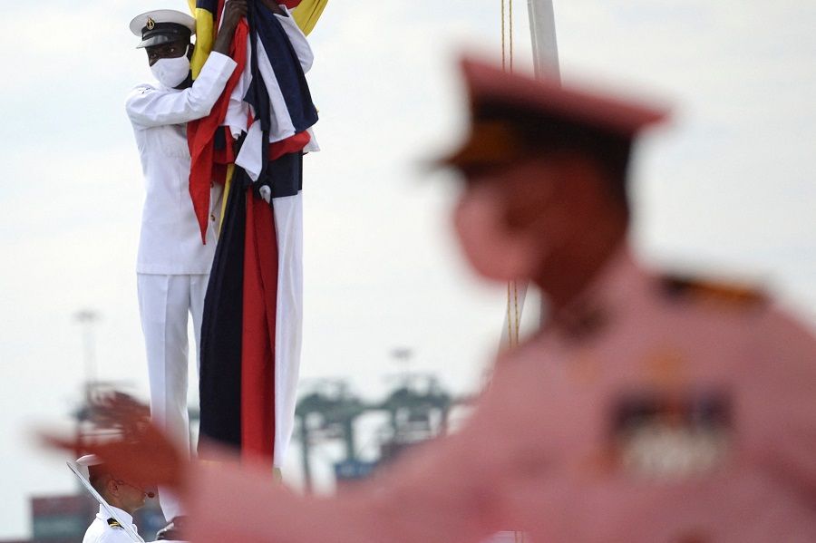 A Coast guard cadet holds a flag on the deck of the Indian Coast Guard offshore patrol vessel 'VIGRAHA' during its commissioning ceremony in Chennai, India, on 28 August 2021. (Arun Sankar/AFP)