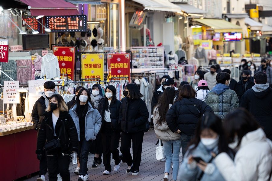People wearing protective masks walk through the Hongdae shopping district in Seoul, South Korea, on 20 February 2022. (SeongJoon Cho/Bloomberg)