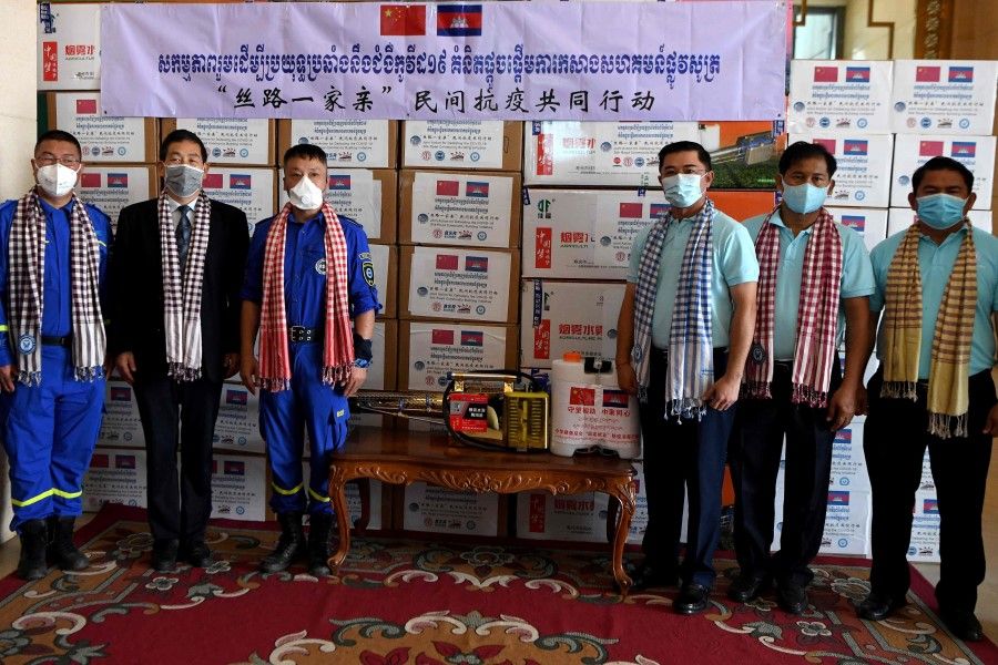 Chinese non-governmental organisation Blue Sky Rescue's Wang Yi(3rd L), China Foundation for Peace and Development's Zhang Yaowu (2nd L) and the Cambodian Civil Society Alliance Forum Kemreat Viseth (3rd R) pose in front of boxes of aid, including medical equipment, donated to Cambodia during a handover ceremony at the Council of Ministers in Phnom Penh, 4 May 2020. (Tang Chhin Sothy/AFP)