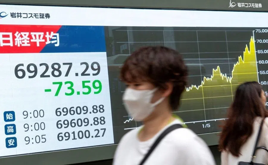 Pedestrians walk past an electronic quotation board displaying the Nikkei Stock Average on the Tokyo Stock Exchange along a street in Tokyo on 29 June 2026.