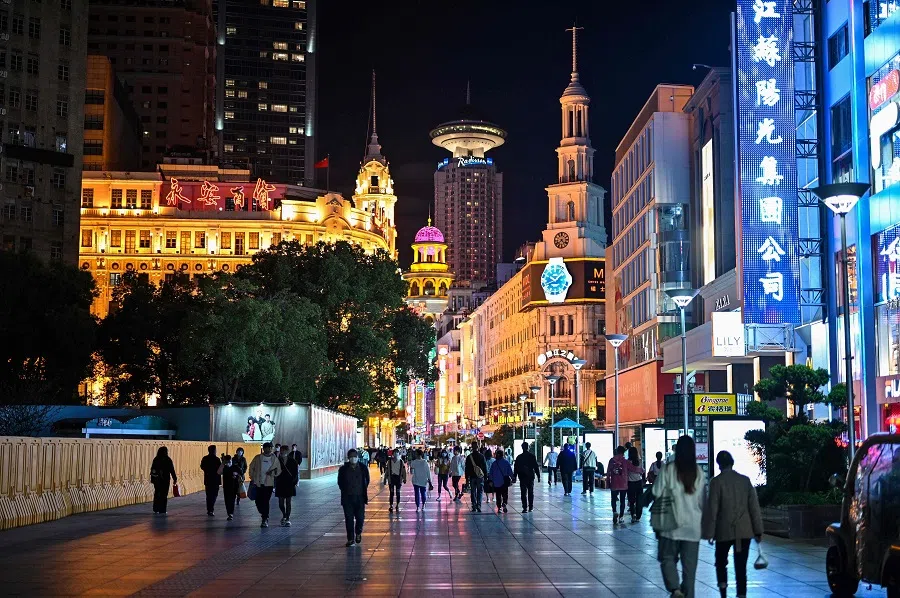 People walk along a pedestrian street surrounded by shops and shopping malls in Shanghai, on 12 October 2022. (Hector Retamal/AFP)