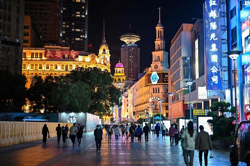 People walk along a pedestrian street surrounded by shops and shopping malls in Shanghai, on 12 October 2022. (Hector Retamal/AFP)