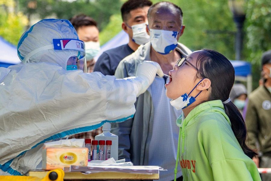 This photo taken on 17 September 2022 shows a health worker taking a swab sample from a young resident to be tested for Covid-19 in Chengdu, Sichuan province, China. (CNS/AFP)
