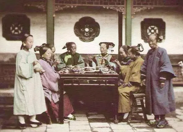Six Manchu women seated around an “eight-immortals table” loaded with rich food in their courtyard. (Wikimedia)