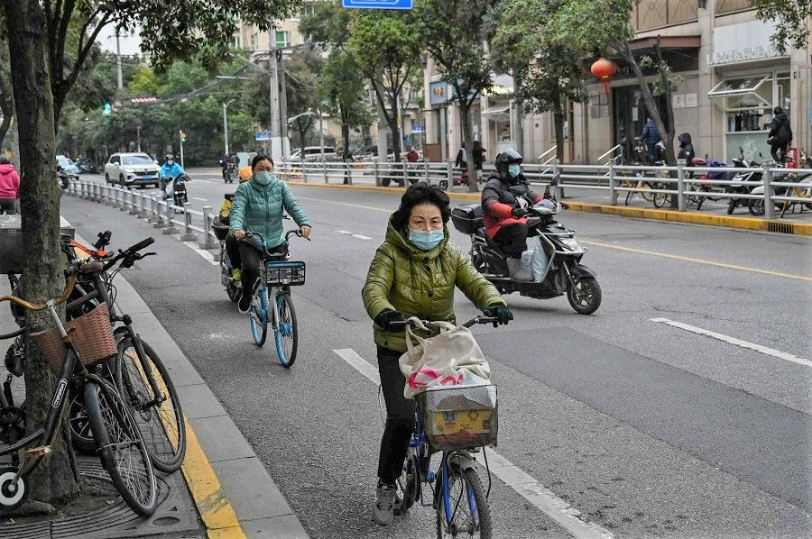 People ride bicycles on a street in Jing'an district, Shanghai, China, on 7 December 2022. (Hector Retamal/AFP)