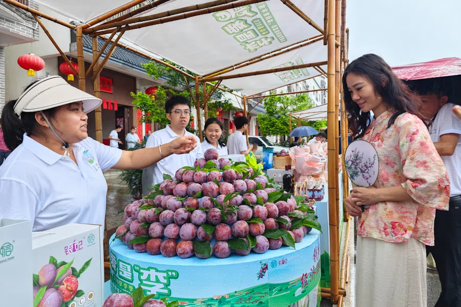A tourist interacts with a local fruit seller in Xinyi county, Guangdong.