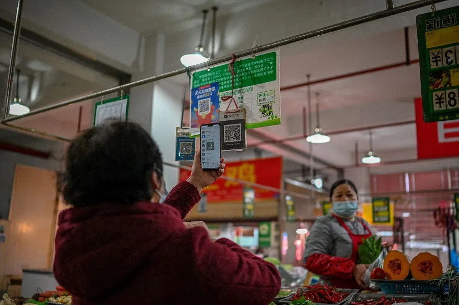 This photo taken on 30 November 2020 shows a woman (left) using her mobile phone to pay for produce at a market in Chengdu, Sichuan province, China. (Noel Celis/AFP)