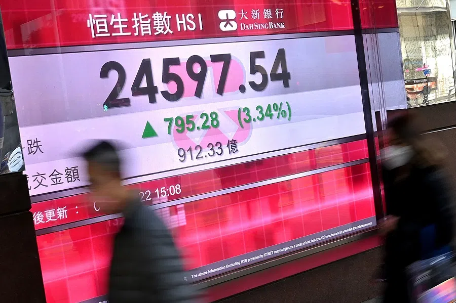 People walk past a sign showing the numbers for the Hang Seng Index before the close on 4 February 2022 in Hong Kong. (Peter Parks/AFP)