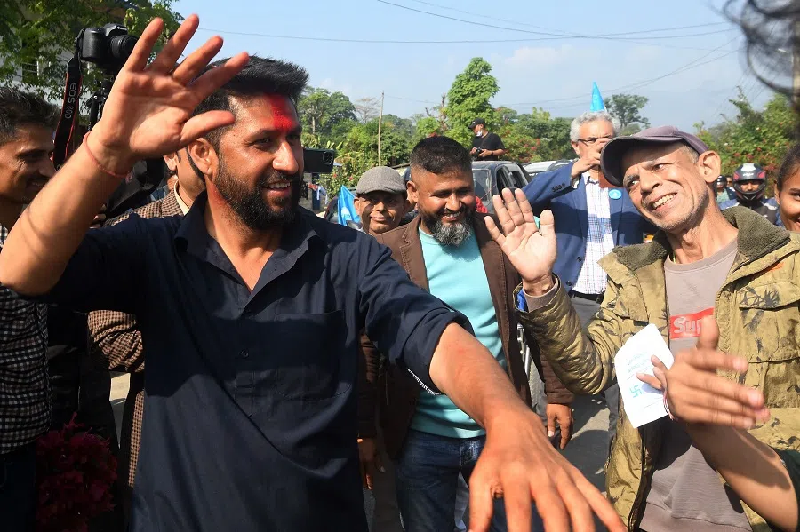 In this picture taken on 12 November 2022, former television host and Independent Party's candidate in Nepal's general election Rabi Lamichhane (left) waves during a door-to-door election campaign event in Padampur. (Prakash Mathema/AFP)