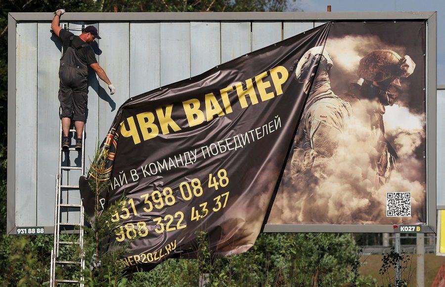 A worker removes an advertising banner promoting service in Wagner private mercenary group on the outskirts of Saint Petersburg, Russia, 24 June 2023. (Anton Vaganov/Reuters)