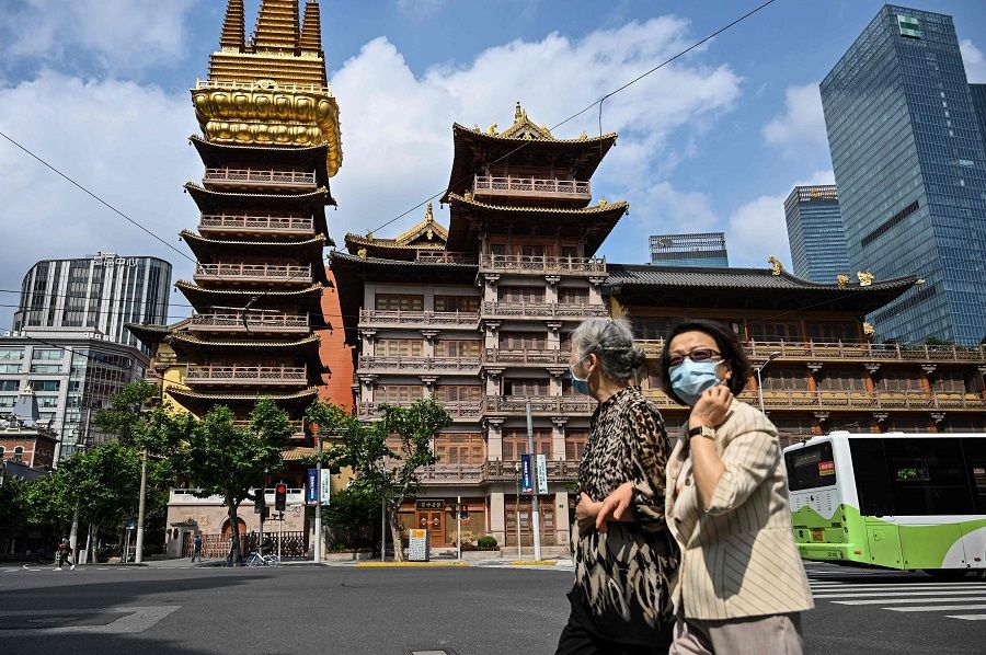 People walk past the Jing'an Temple during a Covid-19 lockdown in the Jing'an district of Shanghai, China, on 25 May 2022. (Hector Retamal/AFP)