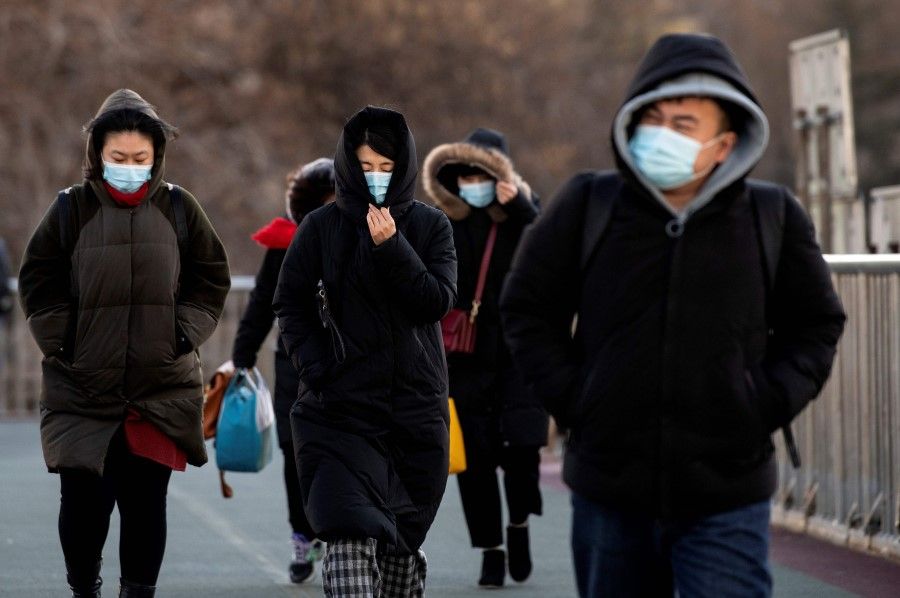 People wrapped up due to freezing weather walk on an overpass in Beijing on 6 January 2021. (Noel Celis/ AFP)