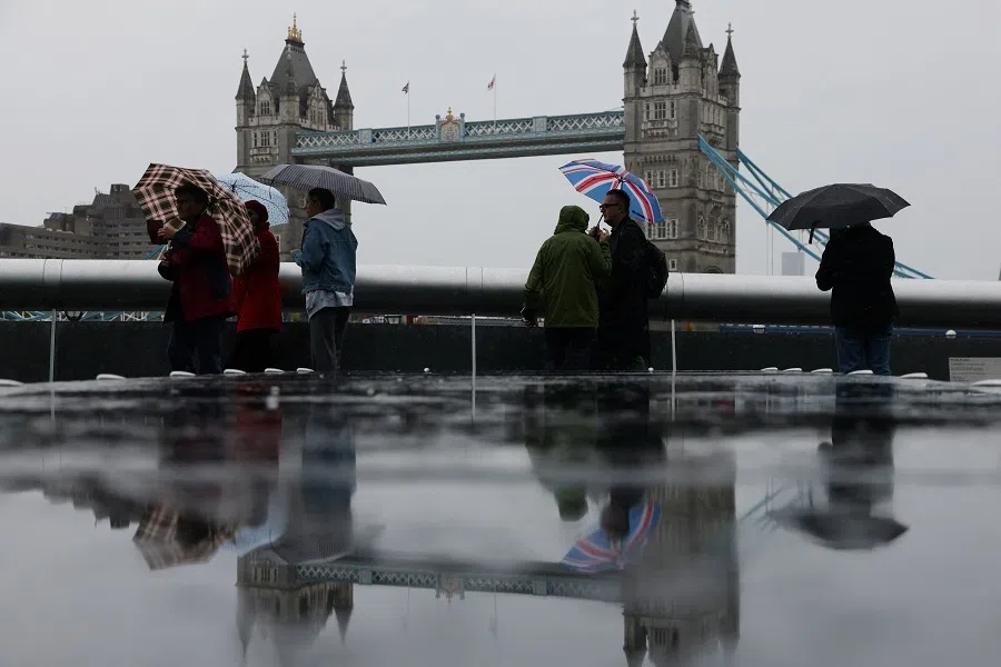 Tourists carrying umbrellas take pictures near Tower Bridge in London, Britain, on 31 July 2023. (Hollie Adams/Reuters)