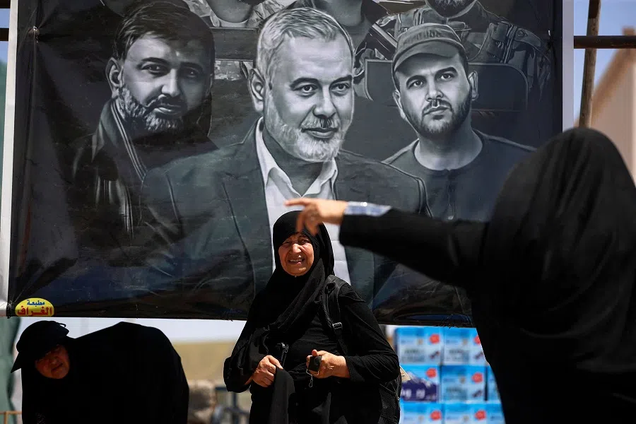 Shiite pilgrims arriving from Iran walk past a billboard depicting slain Hamas political leader Ismail Haniyeh at the Zurbatiyah border crossing in Iraq’s Wasit governorate on 18 August 2024 on their way to the shrine city of Karbala. (Ahmad Al-Rubaye/AFP)