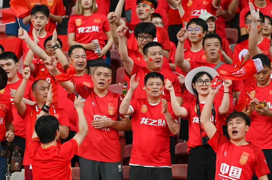Chinese football fans cheer during the FIFA World Cup 2026 qualifier football match between Singapore and China at the National Stadium in Singapore on 21 March 2024. (Roslan Rahman/AFP)