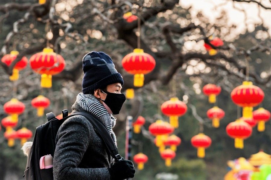A man wears a protective face mask amid the Covid-19 pandemic, as he walks past the Jingshan park overlooking the Forbidden City in Beijing on 25 January 2020. (Nicolas Asfouri/AFP)
