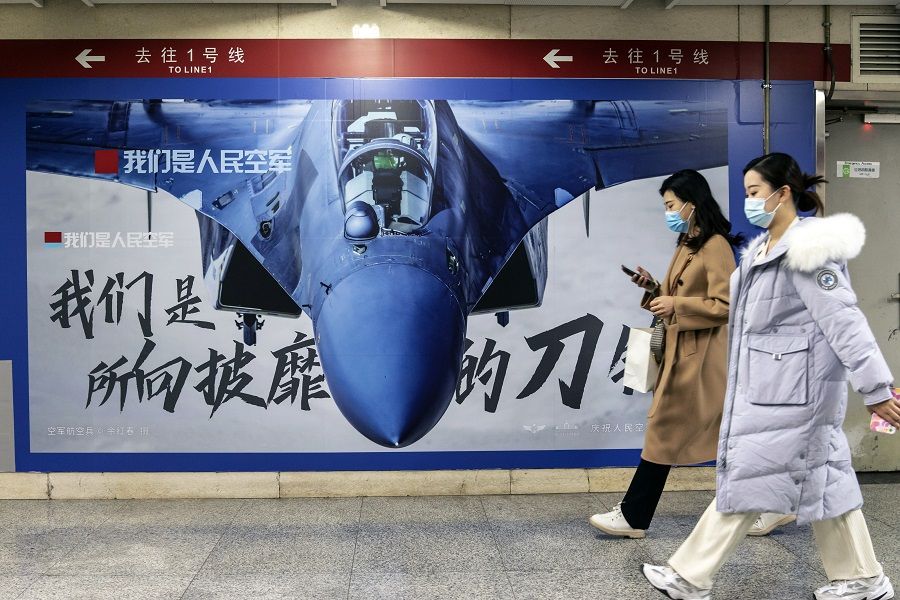 Commuters walk past an advertisement promoting the People's Liberation Army (PLA) Air Force at a subway station in Beijing, China, 22 November 2021. (Qilai Shen/Bloomberg)