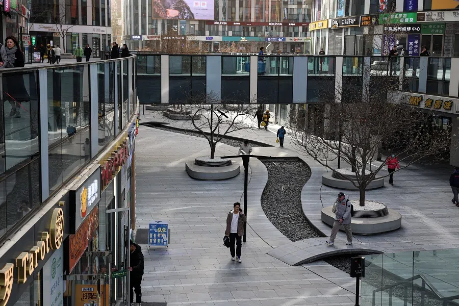 People walk at a shopping compound in Beijing, China, 6 December 2023. (Tingshu Wang /Reuters)