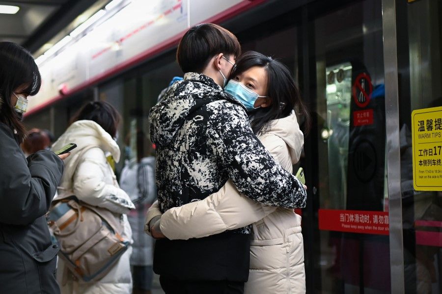 This picture taken on 7 January 2021 shows a couple hugging as they wait for a train at a subway station in Beijing. (Photo by WANG Zhao/AFP)