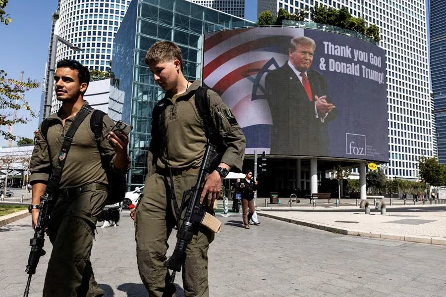Israeli soldiers walk by a billboard commissioned by an evangelical group, which displays a picture of US President Donald Trump with the words "Thank you God & Donald Trump!", amid the US-Israel conflict with Iran, in Tel Aviv, Israel, 12 March 2026. (Nir Elias/Reuters)