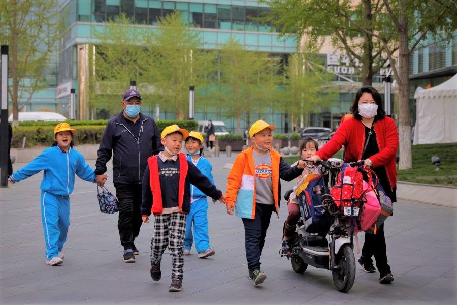 People pick up children from a school in Beijing, China, 6 April 2021. (Thomas Peter/Reuters)