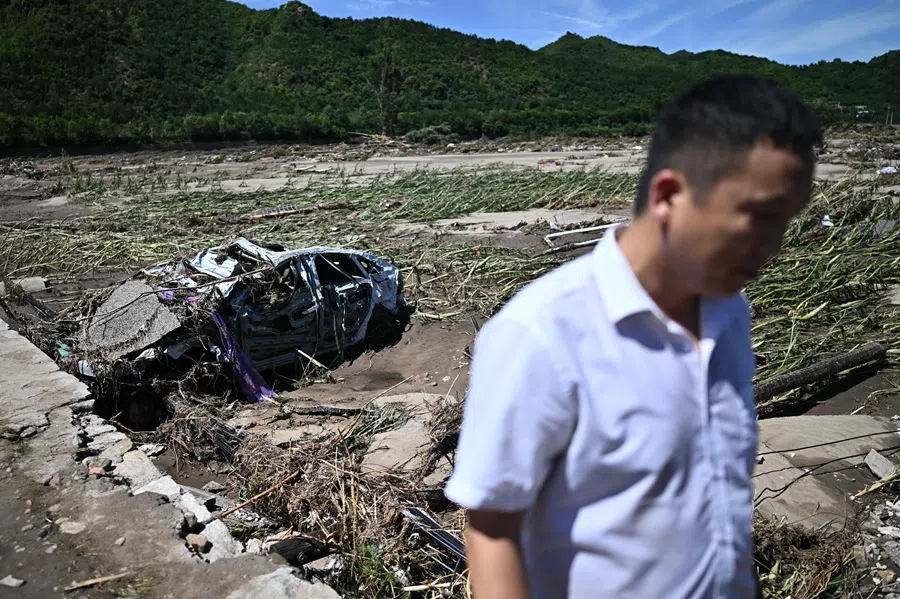 A man walks past a damaged car from floods over the past few days in Huairou district, on the outskirts of Beijing on 30 July 2025. (Pedro Pardo/AFP)