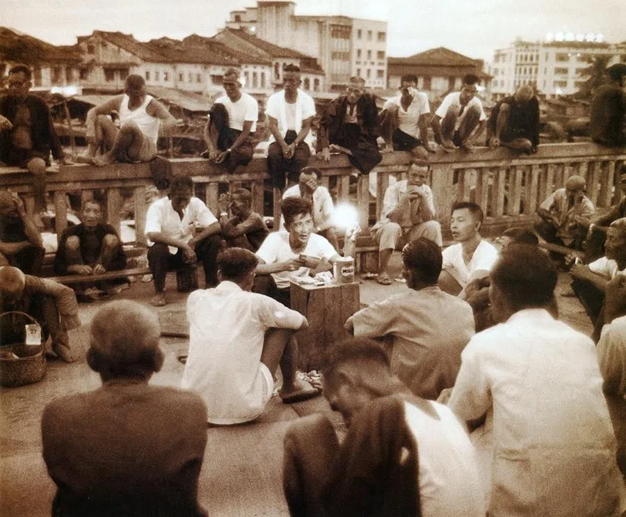 Coolies along the banks of the Singapore River in 1960 looked to storytellers for amusement.