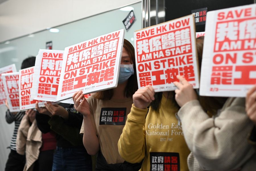 Members of the Hospital Authority Employees Alliance and other medical personnel hold placards during a strike at the Hospital Authority building in Hong Kong on 7 February 2020, calling for the government to close its border with the mainland to contain the virus outbreak. (Philip Fong/AFP)