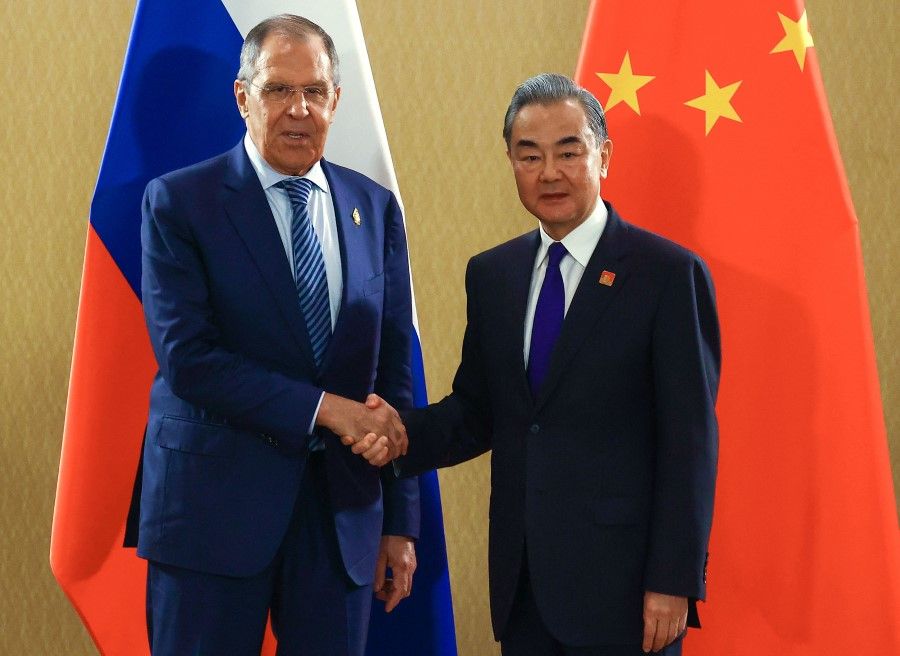 This handout picture taken and released by the Russian Foreign Ministry press service on November 15, 2022, shows Russia's Foreign Minister Sergei Lavrov (left) shaking hands with his Chinese counterpart Wang Yi (right) during their meeting on the sidelines of the G20 leaders' summit in Nusa Dua, on the Indonesian resort island of Bali. (Handout/Russian Foreign Ministry/Handout/AFP)