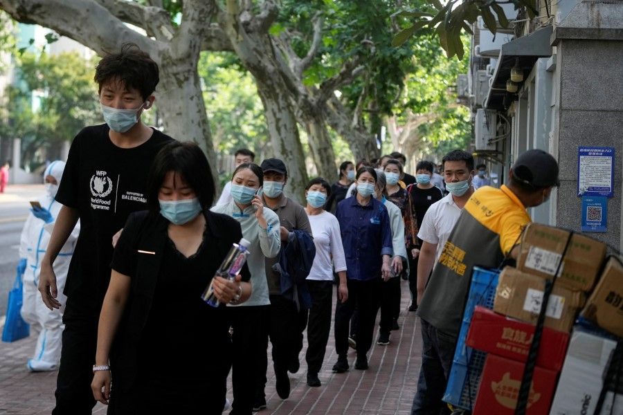 People line up for nucleic acid tests on a street, amid new lockdown measures in parts of the city to curb the Covid-19 outbreak in Shanghai, China, 9 June 2022. (Aly Song/Reuters)